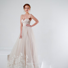 Fototapeta na wymiar Portrait of a beautiful girl in a wedding dress. Bride in luxurious dress on a white background