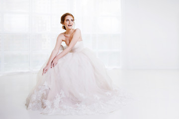 Fototapeta na wymiar Portrait of a beautiful girl in a wedding dress. Bride in luxurious dress sitting on a chair