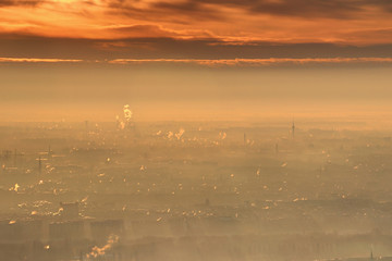 Glowing winter sunrise with bright orange clouds and morning mist over houses, tower blocks and...
