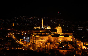 Fototapeta na wymiar Floodlit Buda Castle Hill elevated view in evening lit by exterior lighting with Baroque Royal Palace, medieval fortifications, Matthias Church and city light dots, Budapest Hungarian capital Europe