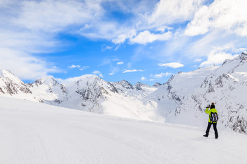 Naklejka na ściany i meble Unidentified woman skier taking picture with smart phone of beautiful mountains during winter season, Obergurgl-Hochgurgl ski area, Austria