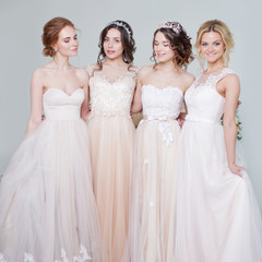 Fototapeta premium Bride in wedding salon. Four beautiful girl are in each other's arms. Back, close-up lace skirts