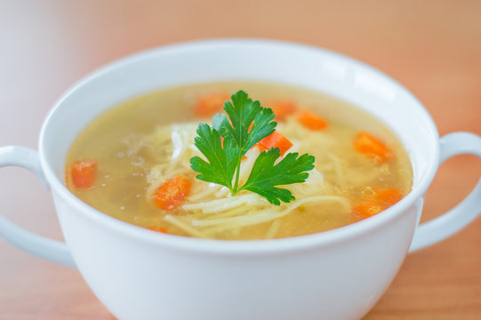 Chicken broth with nudles, carrot and and parsley.