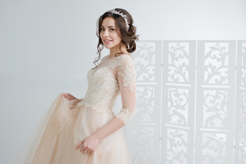 Obraz na płótnie Canvas Portrait of a beautiful girl in a wedding dress. Bride in a luxurious dress, in a beautiful white interior