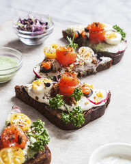 Smorrebrod, traditional Danish open sanwiches, dark rye bread with salmon, cream cheese and capers. Top view.