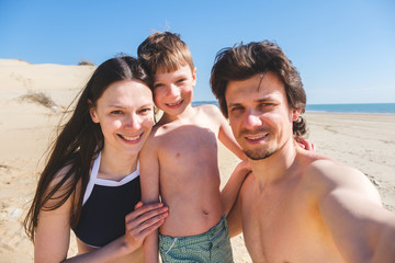 Fototapeta premium Happy family mom, son and dad onthe sand beach with dunes.