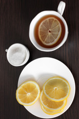 Fototapeta na wymiar Tea with lemon on a wooden background. Tea, lemon and sugar.
