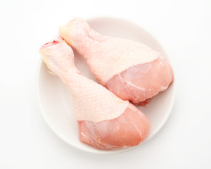 raw chicken legs on white plate, isolated on white
