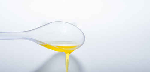 Oil fliesst vom Löffel auf weiß