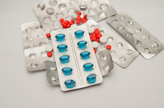 Great number of the spilled red and white pills, and also packing of blue pills of 