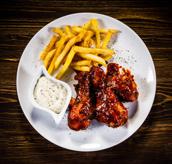 Barbecued drumstick with french fries on wooden table