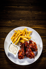 Barbecued drumstick with french fries on wooden table