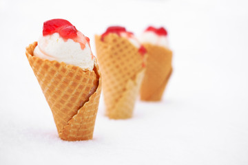 ice cream in waffle cone with red jelly in snow