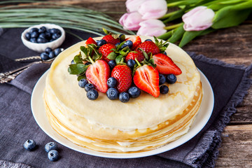 Crepes cake with cottage cheese and strawberry, selective focus on wood table.