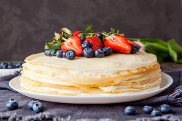 Crepes cake with cottage cheese and strawberry, selective focus on wood table.