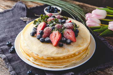 Crepes cake with cottage cheese and strawberry, selective focus on wood table.