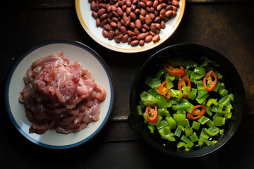 Pieces of chicken, beans. Pepper and chili in a frying pan top view