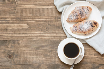 Two delicious freshly baked chocolate croissants and cup of coffee on wooden board. Top view. Breakfast concept.