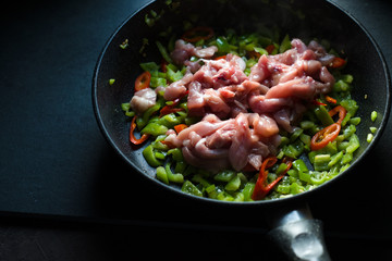 Frying pan with peppers and chicken pieces side view