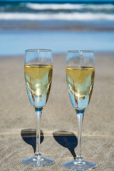 Two glasses of champagne or cava sparkling wine served on the white sandy tropical beach, luxury resort with sea view, romantic vacation