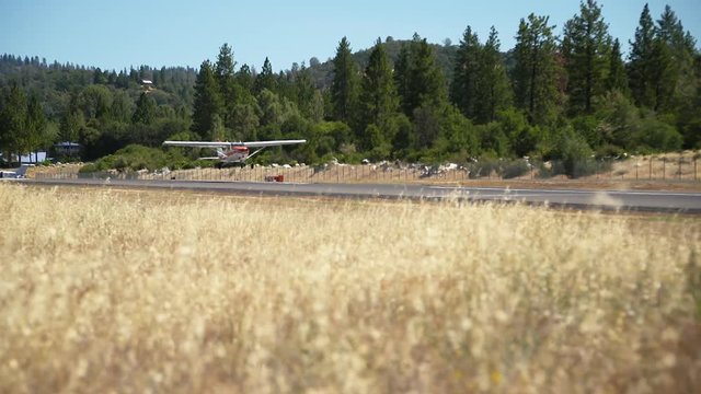 Small supe slow motion, single engine private propeller plane landing on an  airstrip,