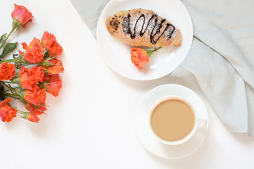 Freshly baked chocolate croissants and cup of coffee on white table. Top view. Female breakfast. Copy space.