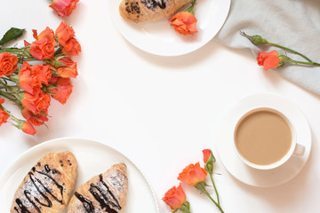 Freshly baked chocolate croissants and cup of coffee on white table. Top view. Female breakfast. Copy space.