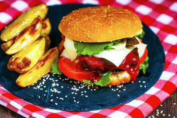 Closeup of home made beef burgers with lettuce served on stone cutting board and table-napkin.