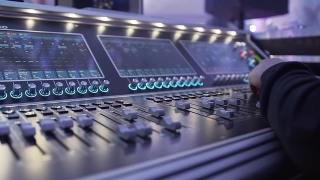 Male Dj hands playing set in night club party. Hands of Audio engineer working on a professional analog console, moving faders, mixing music