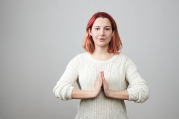 Portrait of cute redhead caucasian female model standing with hands in pray position in white...