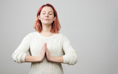 Portrait of cute redhead caucasian female model standing with hands in pray position in white...