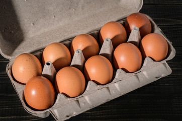 Fresh brown eggs on rustic, wooden, black, dark background