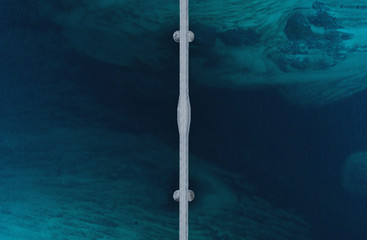 Aerial shot of a bridge over sea strait. Visible depth with blue and green colours near Tromso. Sommaroy, Norway
