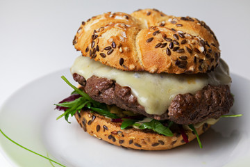 Rustic home made cheesburger with melting cheese and with dijonnaise sauce on white table on white background