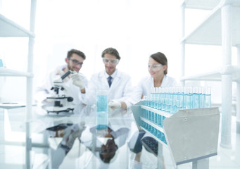 background image of scientists studying blue liquid in a flask