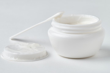 Open jar with face cream on a white background