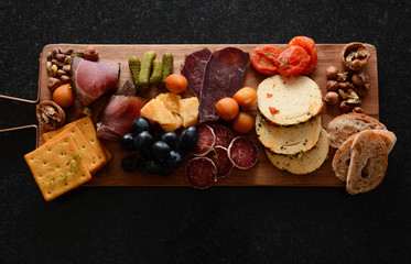 Cheese plate on a board. A different cheese with meat. Snack jamon, prosciutto, camembert, parmesan, olive, Basiron Pesto with basil. Tapas bar. Top view.