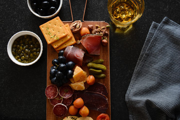 Cheese plate on a board. A different cheese with meat. Snack jamon, prosciutto, camembert, parmesan, olive, Basiron Pesto with basil. Tapas bar. Top view.