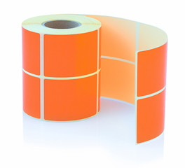 Orange label roll isolated on white background with shadow reflection. Color reel of labels for...