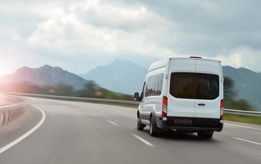 passenger bus van accelerating on a background of mountains - obrazy, fototapety, plakaty