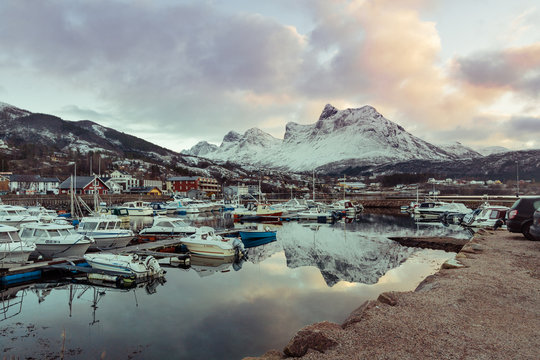Harbor with moored boats and yachts with snow-capped peaks in the background in the village of Orsen, Norway.