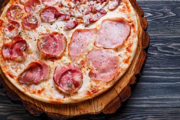 Delicious yummy fresh pizza with bacon, salami, ham and pepperoni and appetizing crust, close up. Italian food, pizzeria