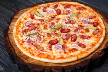Appetizing pizza with salami, onions and gherkins and crunchy crust close up. Italian food, restaurant menu
