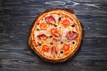 Hot fresh sicilian pizza with bacon, olives and tomatoes served on wood, flat lay. Italian food, restaurant or pizzeria concept