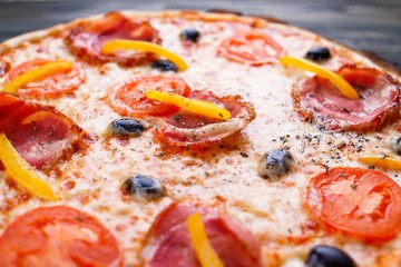 Close up texture of delicious sicilian pizza with bacon, olives and tomatoes, food background
