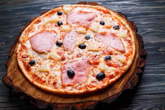 Delicious pizza with ham and black olives on wood, close up. Italian food, restaurant menu photo