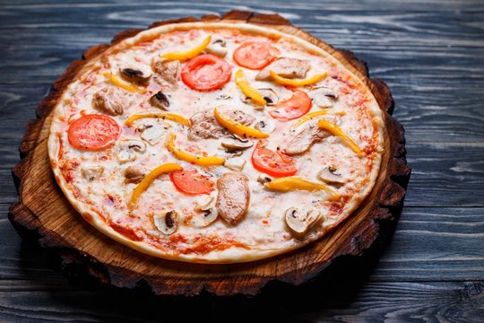 Delicious pizza with tomato, chicken, paprika and mushrooms on wood, close up. Italian food, restaurant menu photo