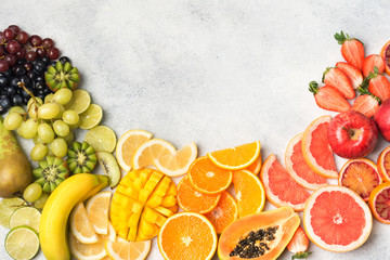 Raw eating, fruits in rainbow colours, strawberries, mango, grapes, bananas, grapefruit on the off white table, copy space for text, selective focus
