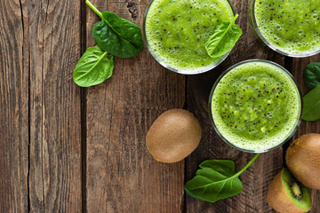 Kiwi smoothie drink of spinach leaves and fresh fruits on wooden rustic table, healthy detox diet