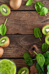 Kiwi smoothie drink of spinach leaves and fresh fruits on wooden rustic table, healthy detox diet